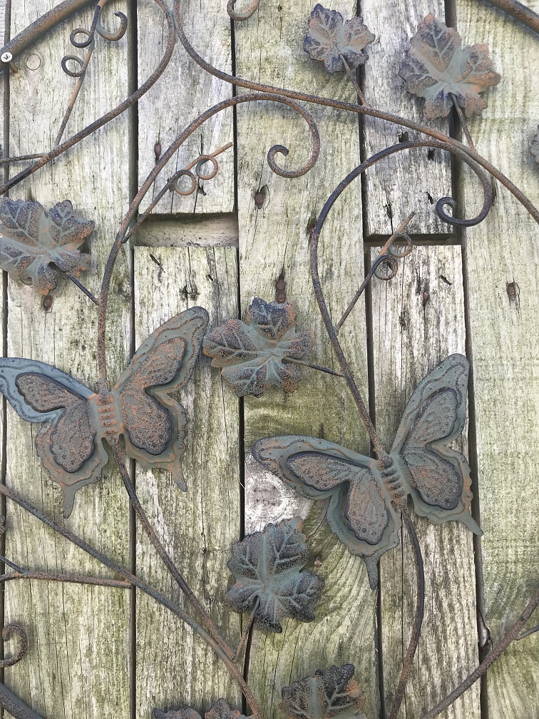 Een metalen wandornament met bladeren en vlinders, zeer decoratief! -